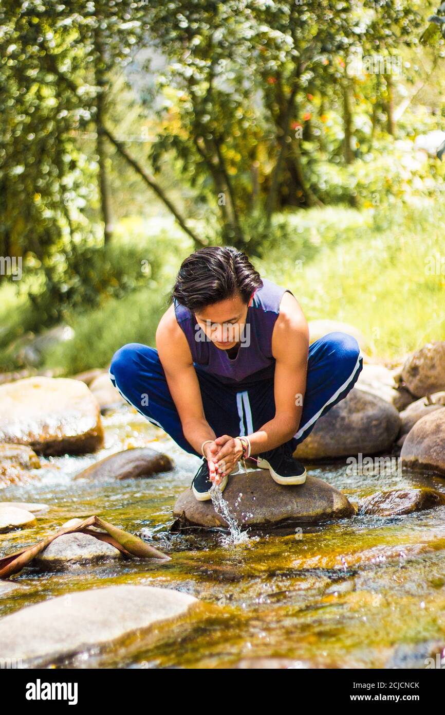 Man standing on the rocks and washing his face in the river Stock Photo ...