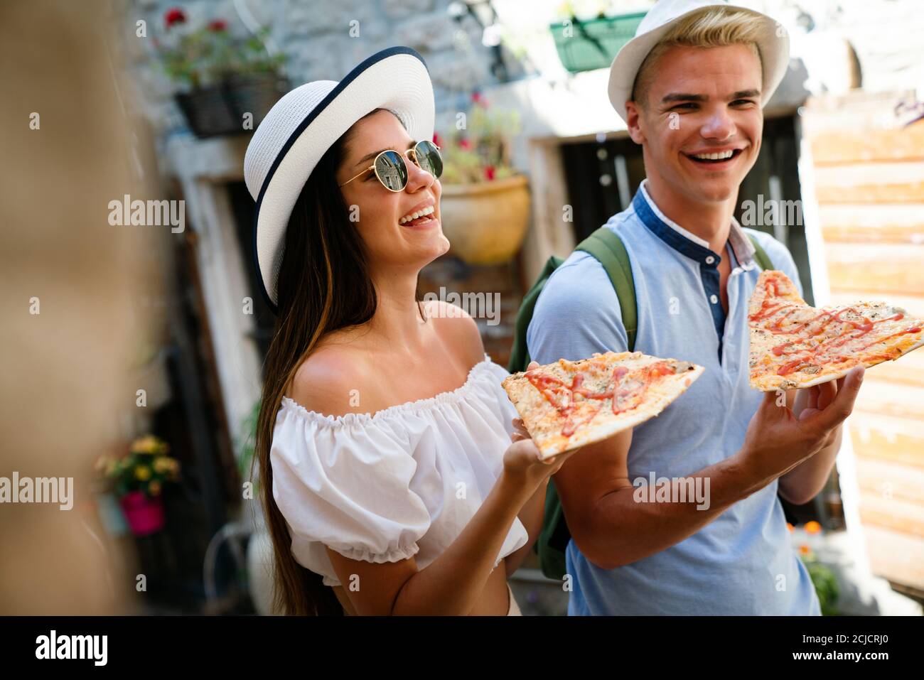 Happy group of people eating pizza outdoors,they are enjoying together ...