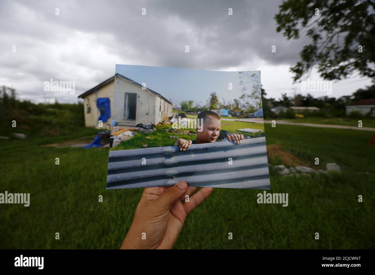 Photographer Carlos Barria holds a print of a photograph he took in 2005, as he matches it up at the same location 10 years on, in Lafitte, south of New Orleans, United States, August 16, 2015. The print shows Tyler Teal cleaning up his home, September 14, 2005, after Hurricane Katrina struck. In 2005, Hurricane Katrina triggered floods that inundated New Orleans and killed more than 1,500 people as storm waters overwhelmed levees and broke through floodwalls. Congress authorised spending more than $14 billion to beef up the city's flood protection after Katrina and built a series of new barri Stock Photo