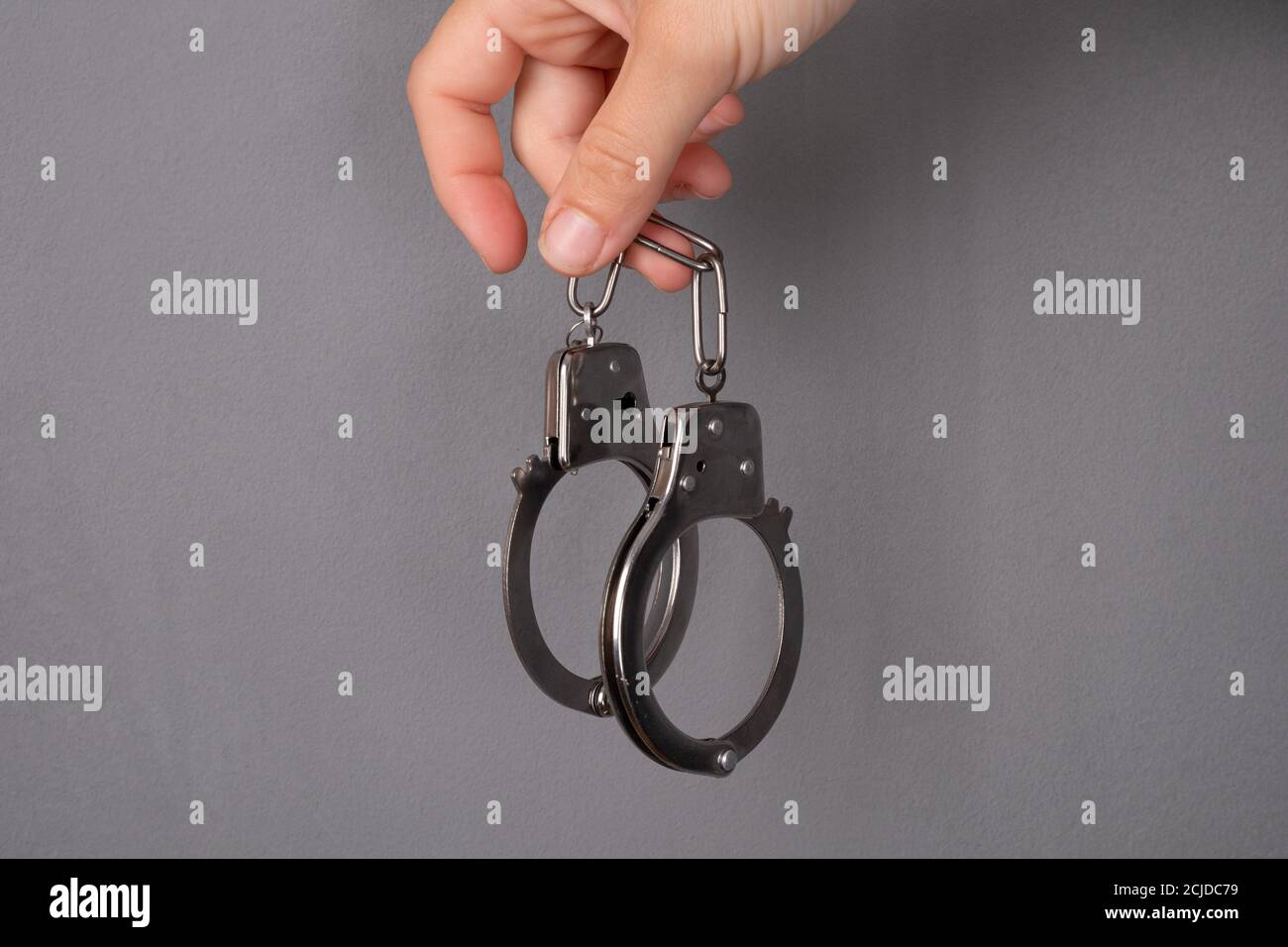 handcuffs on gray background, punishment for a crime. Stock Photo