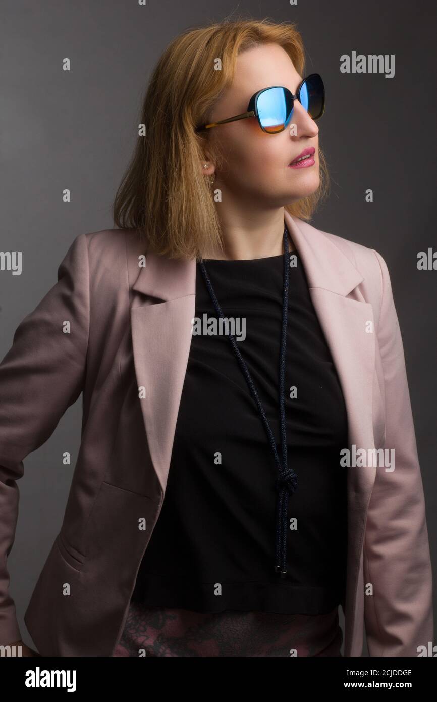 An overweight adult woman wearing sunglasses and black and pink clothing. Studio portrait on a black background Stock Photo