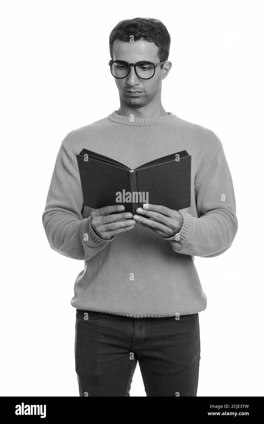 Portrait of young handsome Persian man reading book with eyeglasses Stock Photo