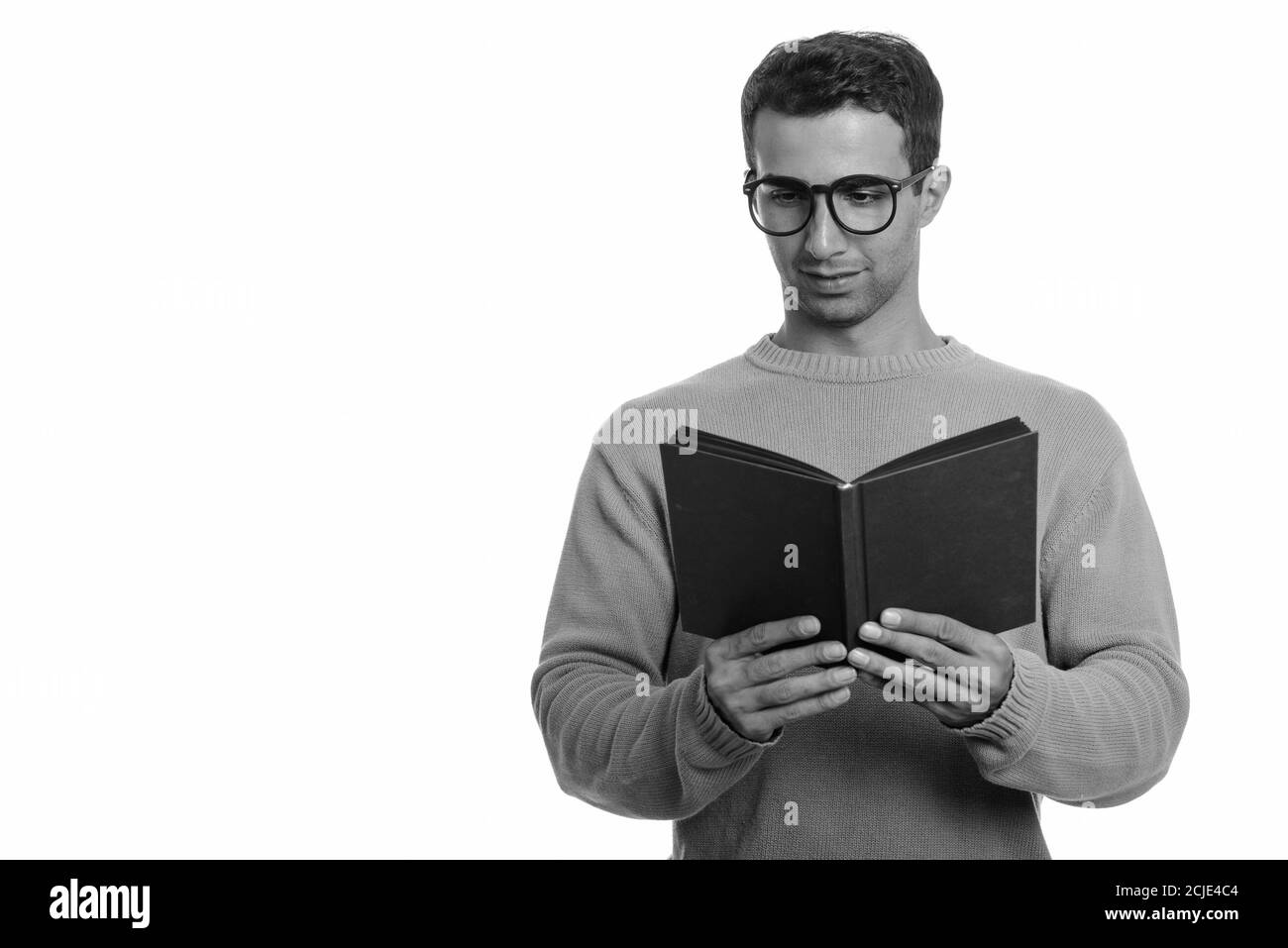 Young happy Iranian man smiling and reading book Stock Photo