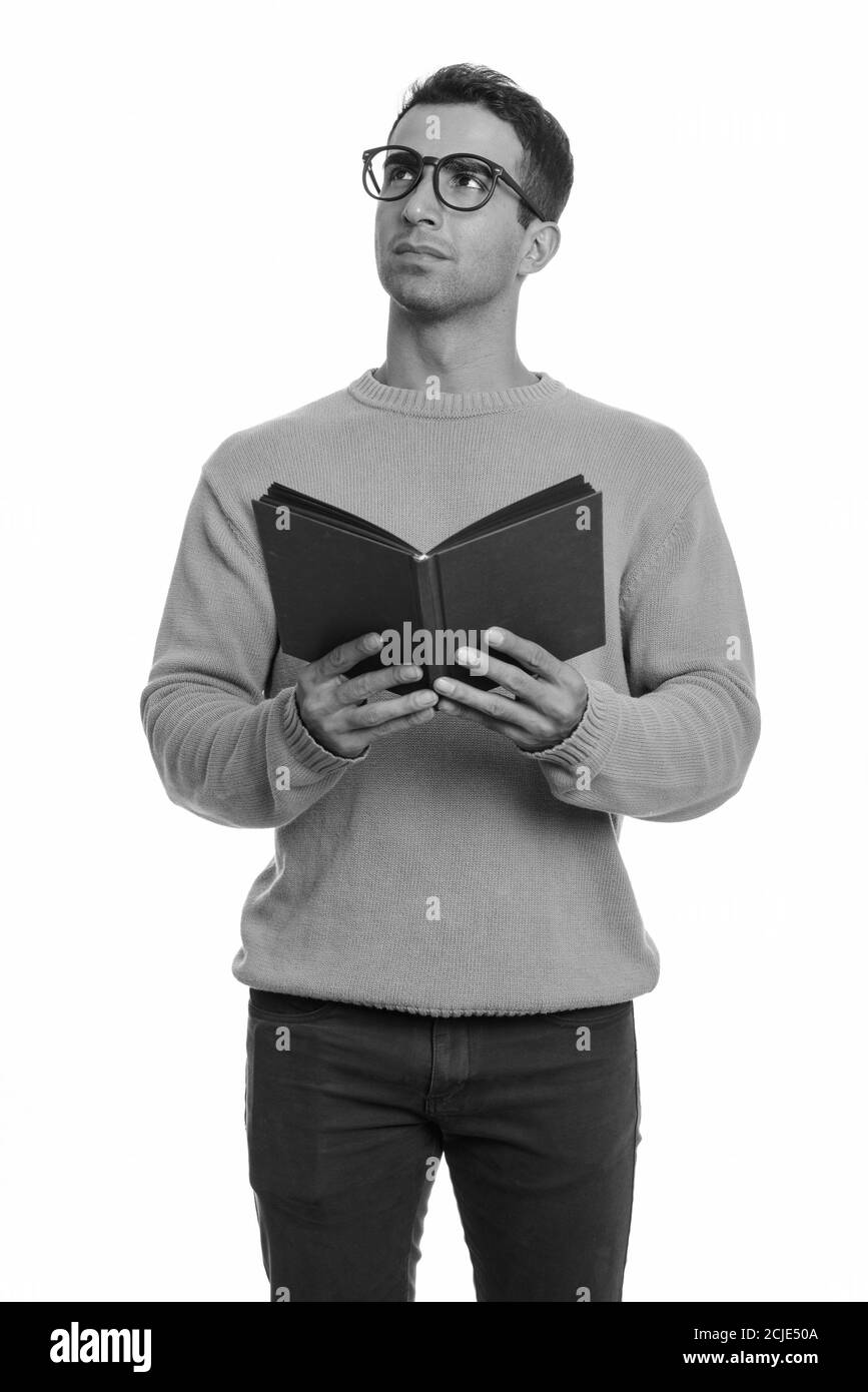 Young handsome Iranian man holding book while thinking Stock Photo