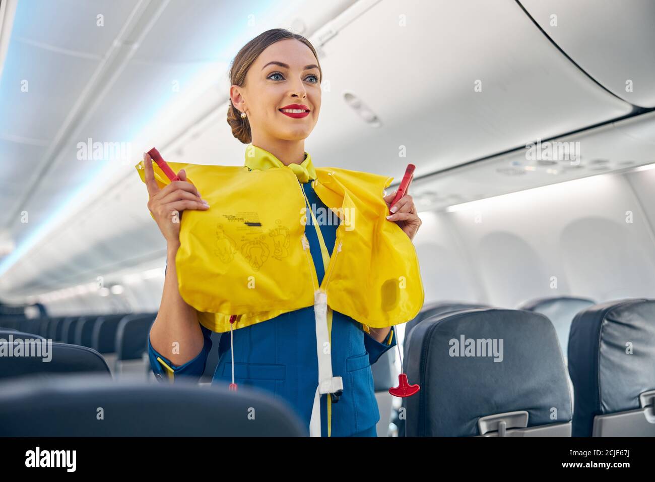 Flight attendant on board an airplane holding life jacket before flight  procedure Stock Photo - Alamy