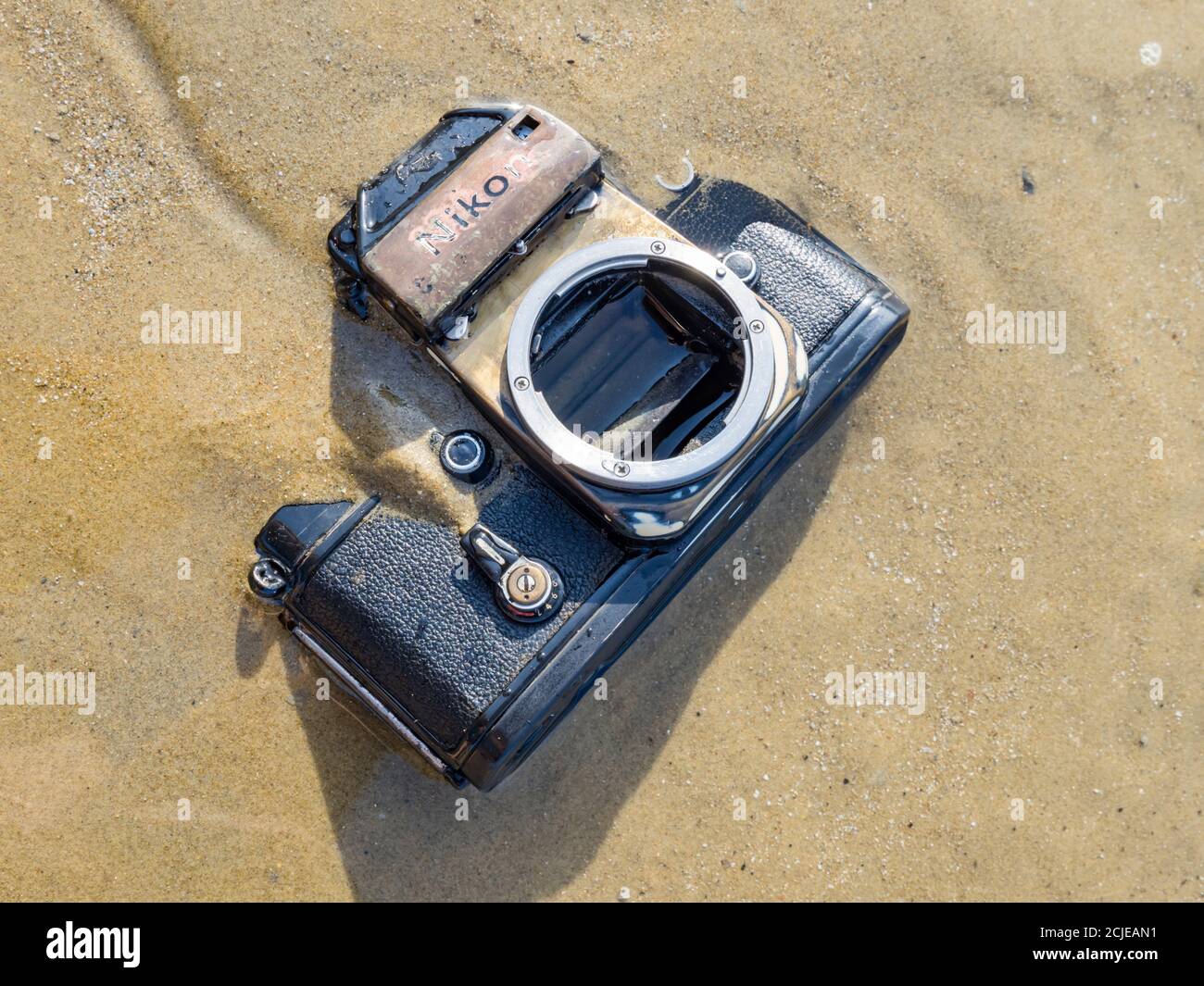 Nikon retro classic SLR film camera on beach rub rubbed down surface and waterlogged Stock Photo
