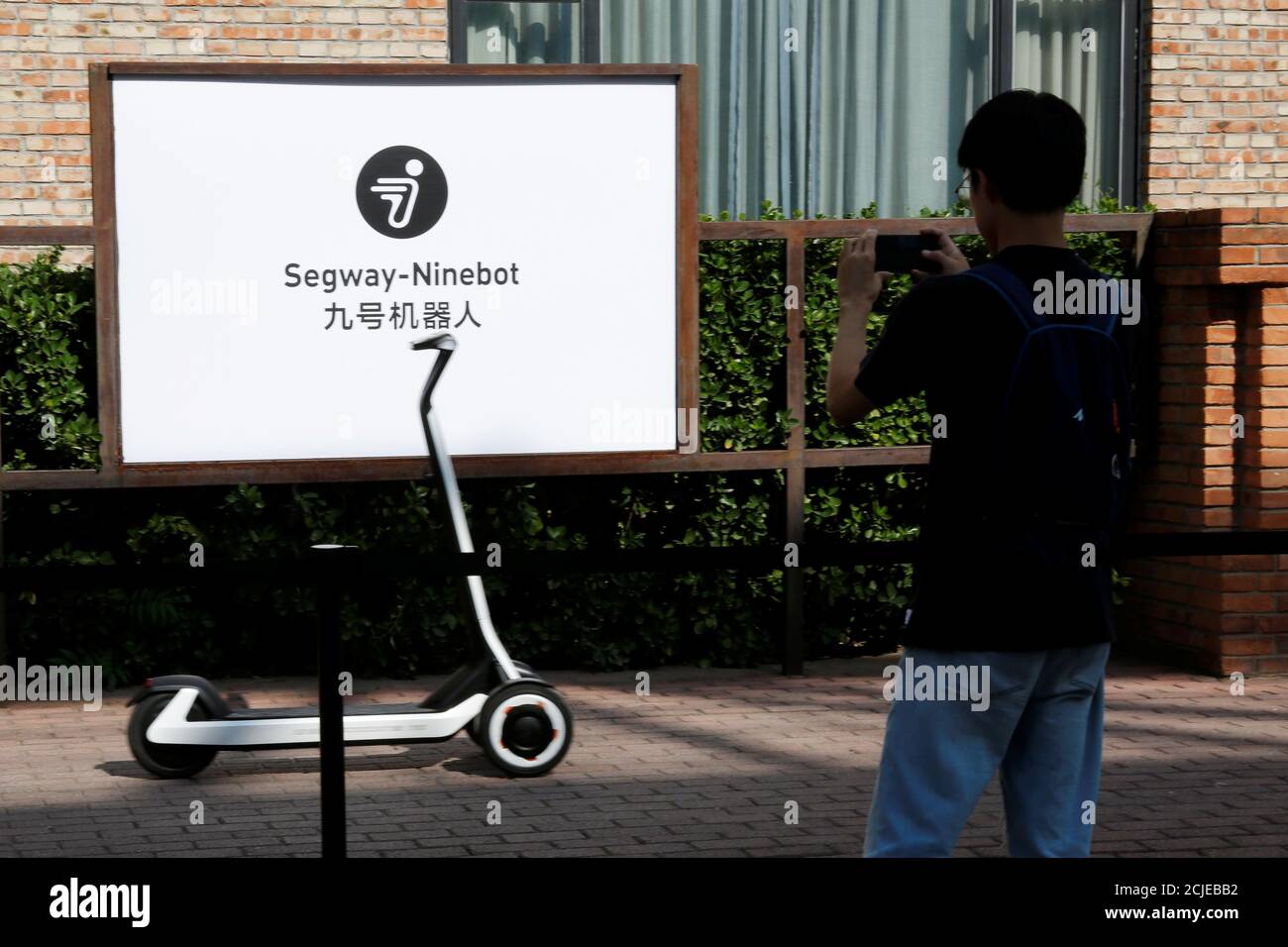 A man takes pictures of a semi-autonomous scooter KickScooter T60 that can  return itself to charging stations without a driver, at a Segway-Ninebot  product launch event in Beijing, China August 16, 2019.