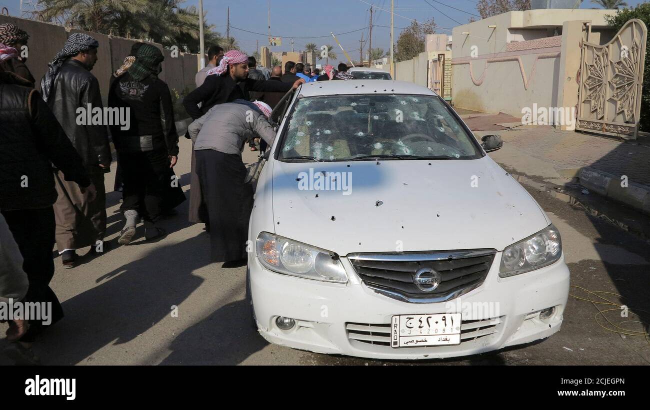 Residents inspect a bullet-riddled car outside the house of prominent Sunni Muslim lawmaker Ahmed al-Alwani in the centre of Ramadi, December 28, 2013.  Iraqi security forces arrested Alwani, a supporter of anti-government protests, in a raid on his home in the western province of Anbar, sparking clashes in which at least five people were killed, police sources said. They said those killed in the fighting included three of Alwani's bodyguards, his sister and his brother. REUTERS/Ali al-Mashhadani (IRAQ - Tags: POLITICS CIVIL UNREST) Stock Photo