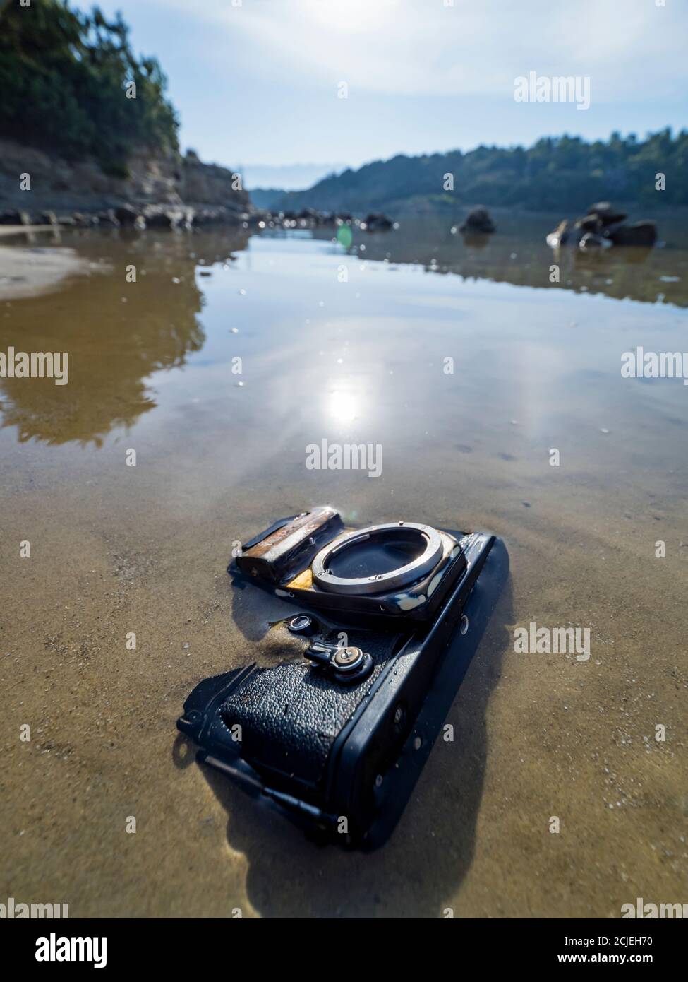 Nikon retro classic SLR film camera on landscape seascape seaside beach sun bright reflection smooth calm sea water surface Stock Photo