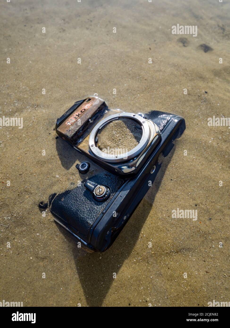 Nikon retro classic SLR film camera on beach covered filled with sand Stock Photo