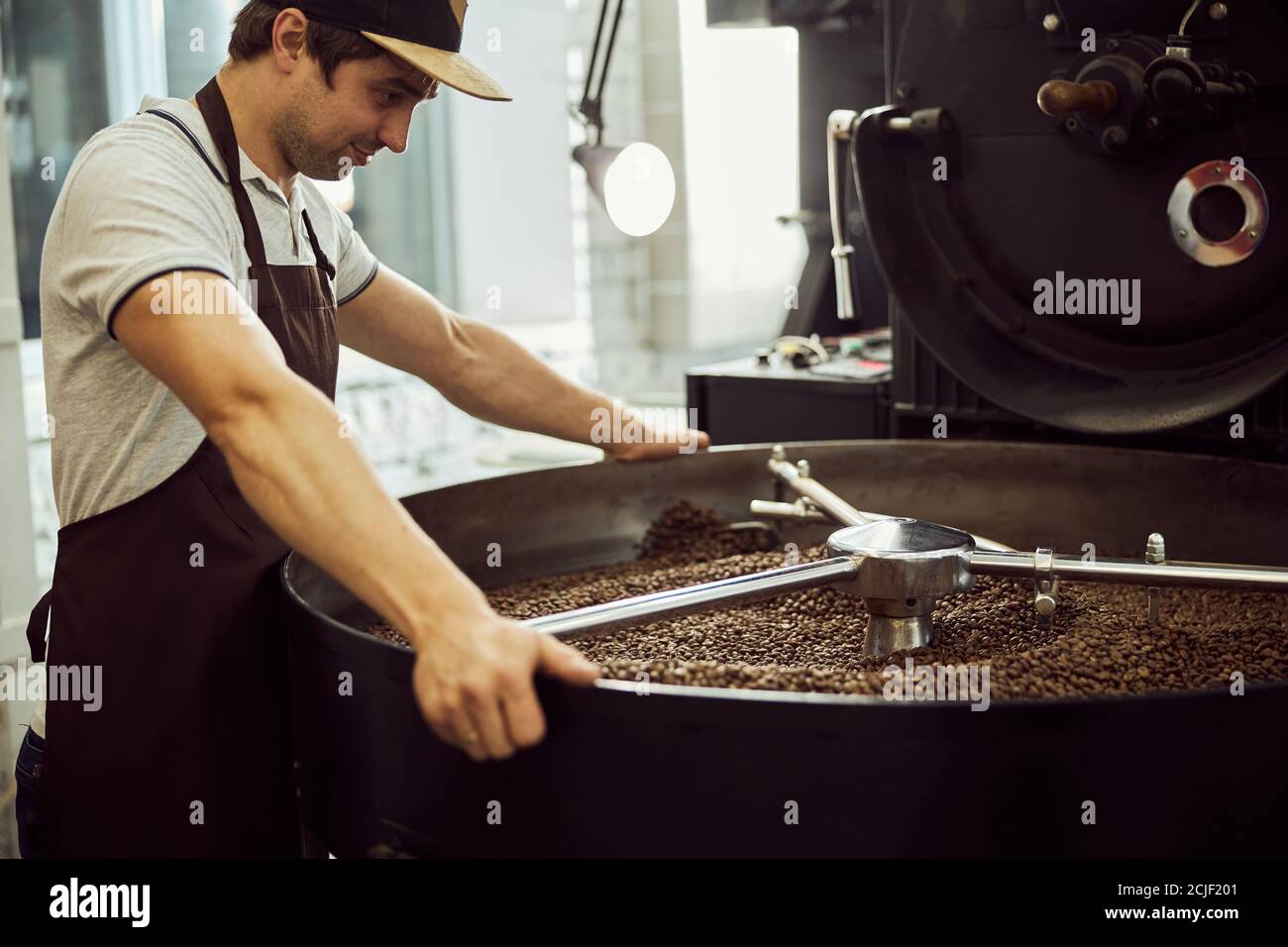Handsome male worker using professional coffee roasting machine Stock Photo