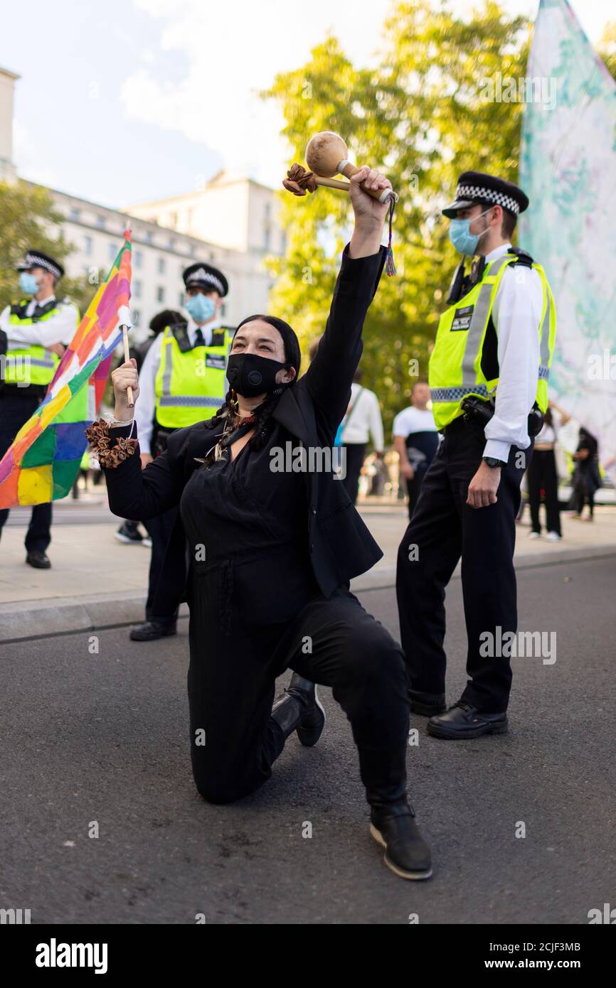 A protester kneeling with maraca, 'Rebels for Amazonia' Extinction Rebellion march on Indigenous Womens Day, London, 5 September 2020 Stock Photo