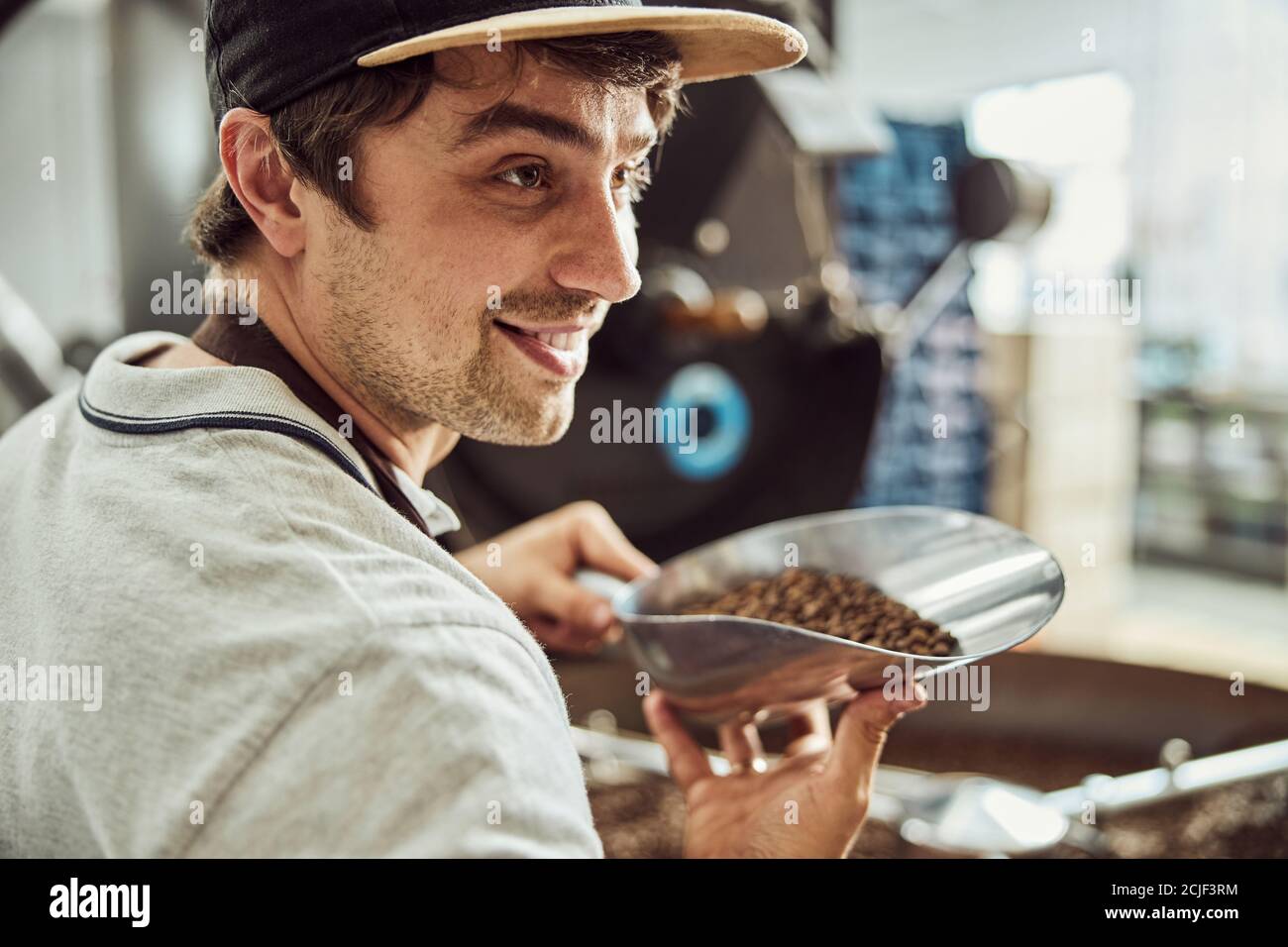 Handsome young man holding scoop with coffee beans Stock Photo