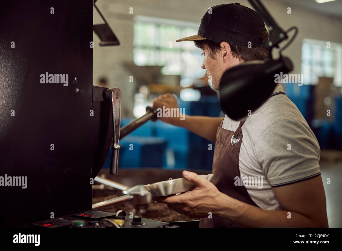 Male worker using industrial coffee roasting machine Stock Photo