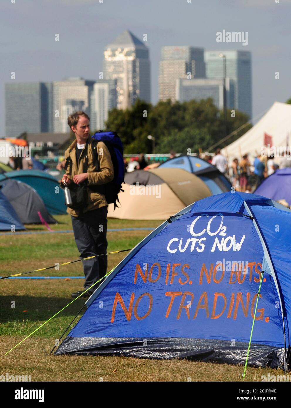 An environmental protester stands next to a camp set up in Blackheath with the Canary Wharf financial district visible behind in southeast London August 27, 2009. Environmentalists demanding an overhaul of the world economy to help save the planet met in London on Wednesday for a week-long camp, one of the biggest tests of the capital's police since the G20 demonstrations. REUTERS/Toby Melville (BRITAIN CONFLICT ENVIRONMENT) Stock Photo