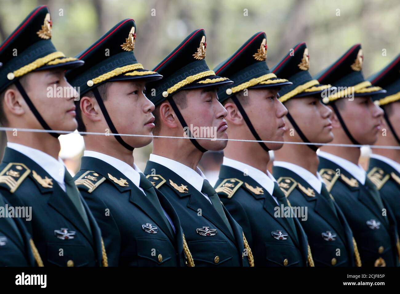 Members of a Chinese People's Liberation Army (PLA) honour guard stand  behind a string to ensure that they are in a straight line before a  welcoming ceremony for Swiss President Johann Schneider-Ammann