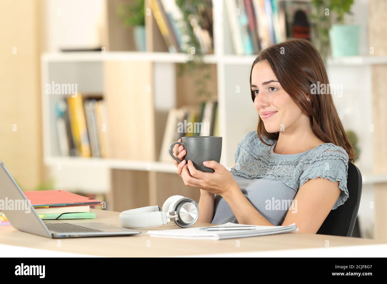 Relaxed student resting drinking coffee contemplating sitting at home Stock Photo