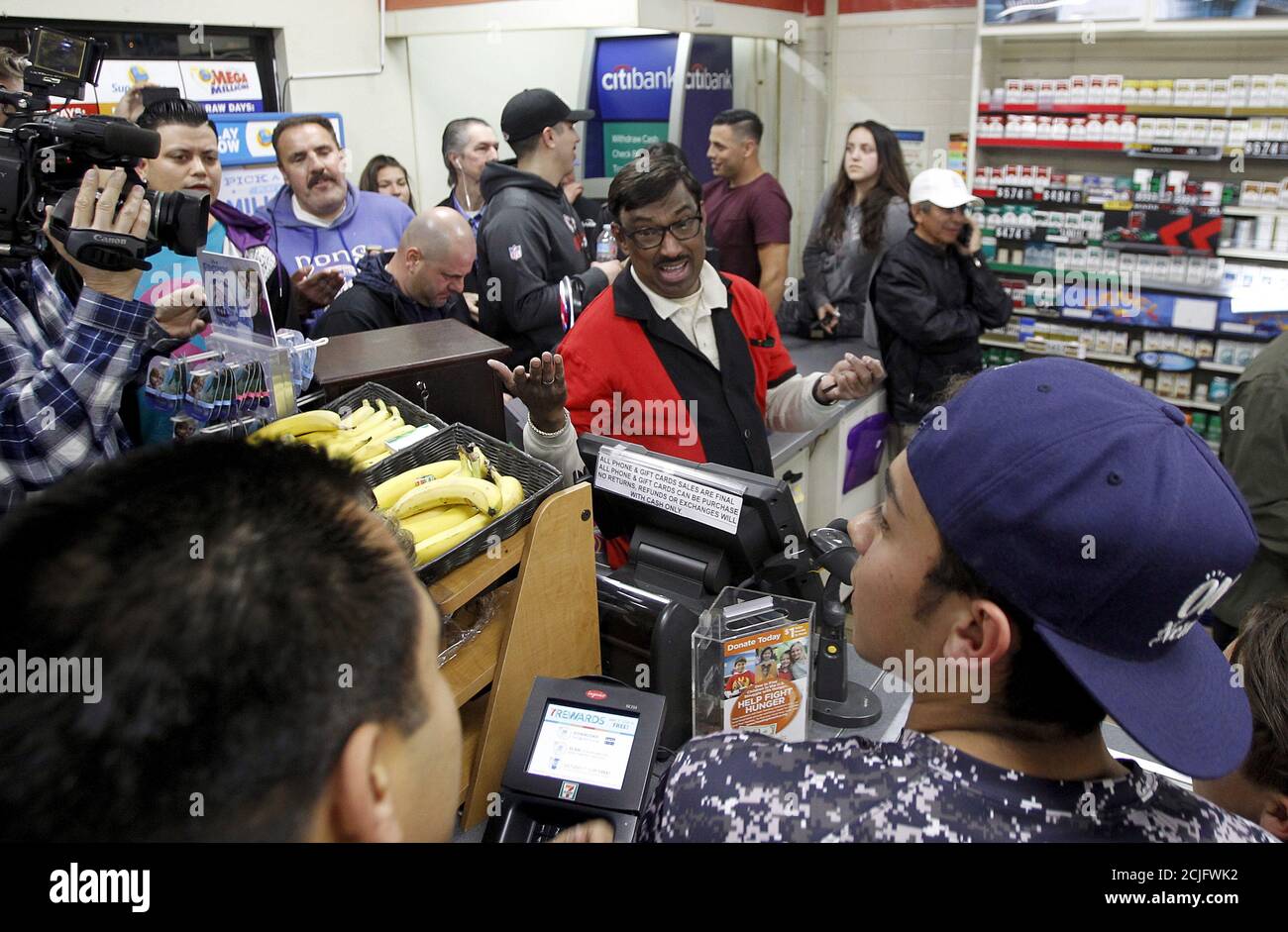 7-Eleven store clerk M. Faroqui (C) celebrates after selling a winning Powerball ticket, in Chino Hills, California January 13, 2016. A winning ticket was sold there for the massive $1.59 billion Powerball lottery on Wednesday, officials said after drawing the winning numbers for the world's largest potential jackpot for a single player. REUTERS/Alex Gallardo Stock Photo