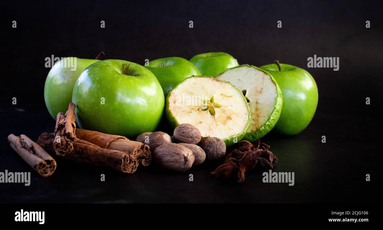 Fresh and dried green applies and whole spices on dark background Stock Photo