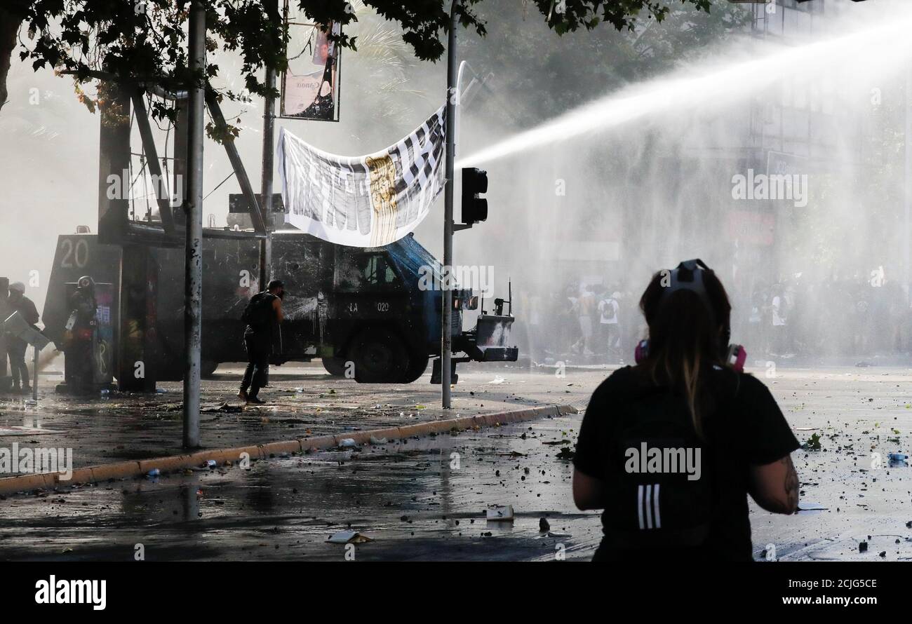 A riot police van shoots a water cannon to disperse demonstrators during a protest against Chile's state economic model in Santiago, Chile October 24, 2019. REUTERS/Henry Romero Stock Photo