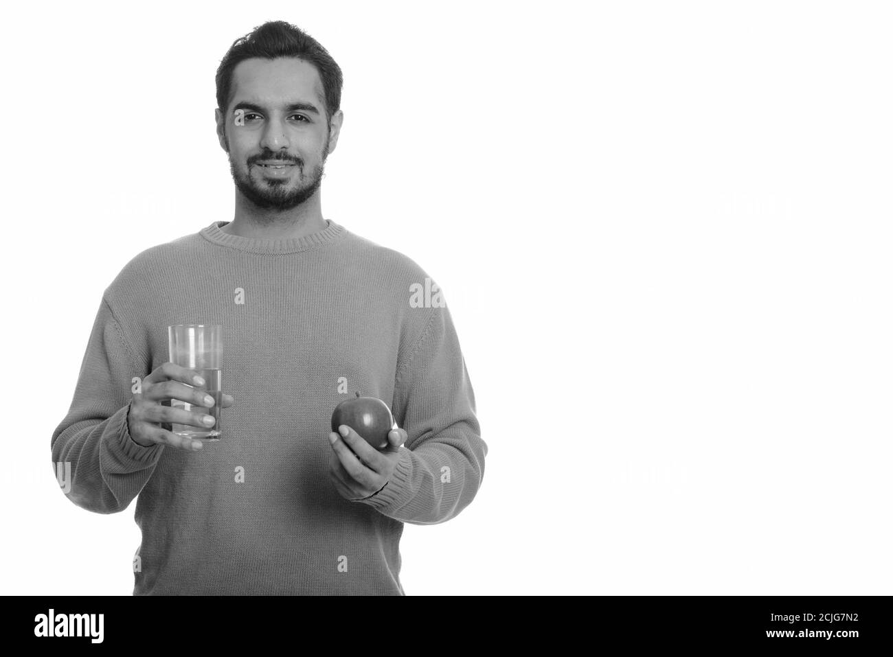 Young happy Indian man holding red apple and glass of water Stock Photo ...
