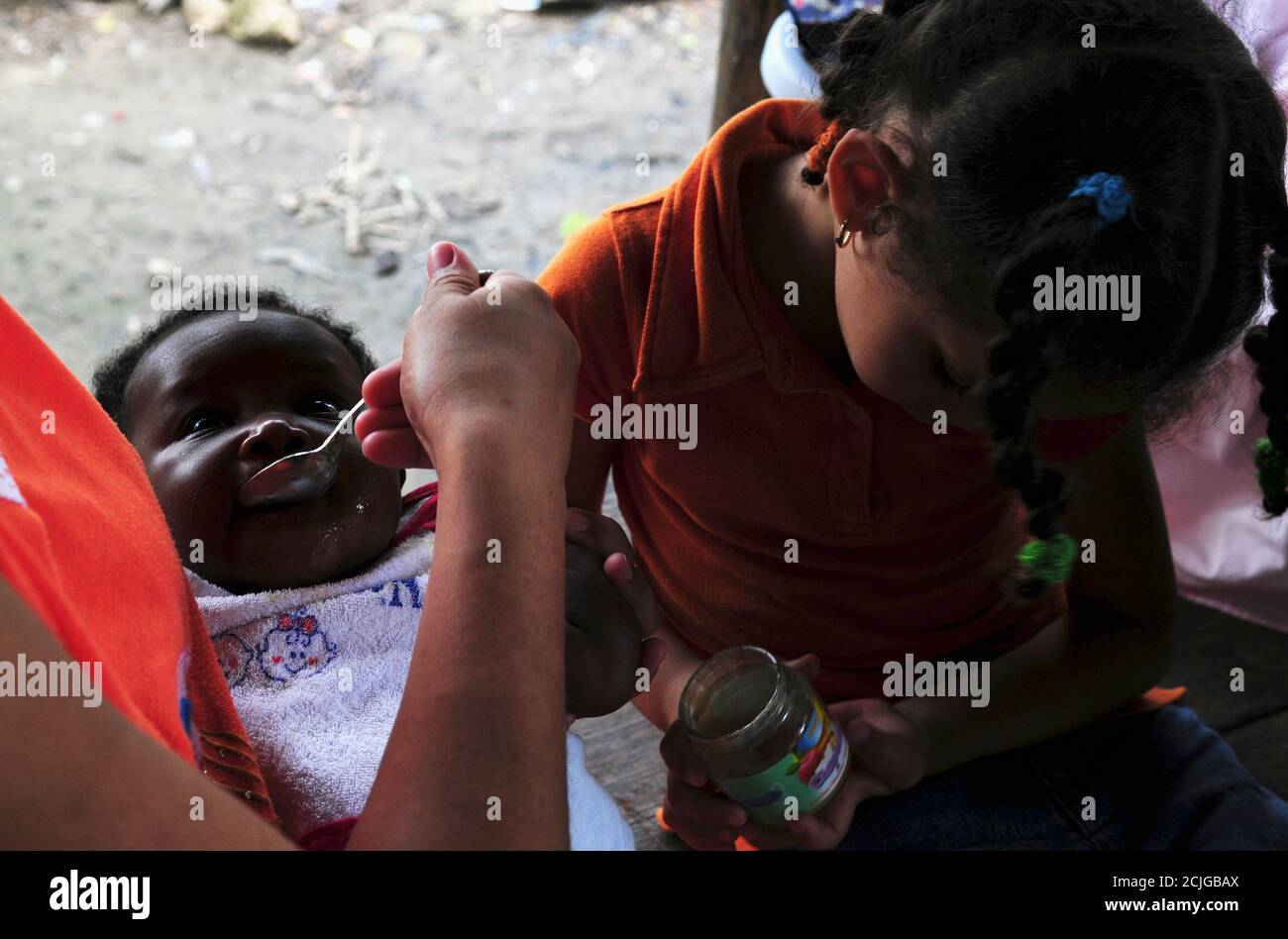 A Haitian Dominican baby is fed by neighbours in El Arenoso in Tamboril April 28, 2012. Cholera cases have been rising in the Dominican Republic, the Health Ministry said. 523 cases have been reported in hospitals and 7 have died, in the district of Tamboril.  REUTERS/Ricardo Rojas (DOMINICAN REPUBLIC - Tags: HEALTH) Stock Photo