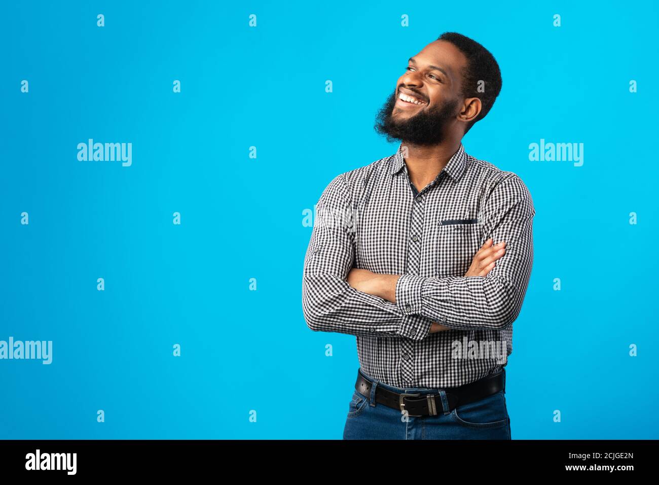 Smiling black man with folded arms posing on blue background Stock Photo