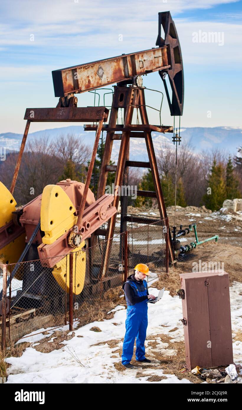 Full length of petroleum engineer in work overalls and helmet checking