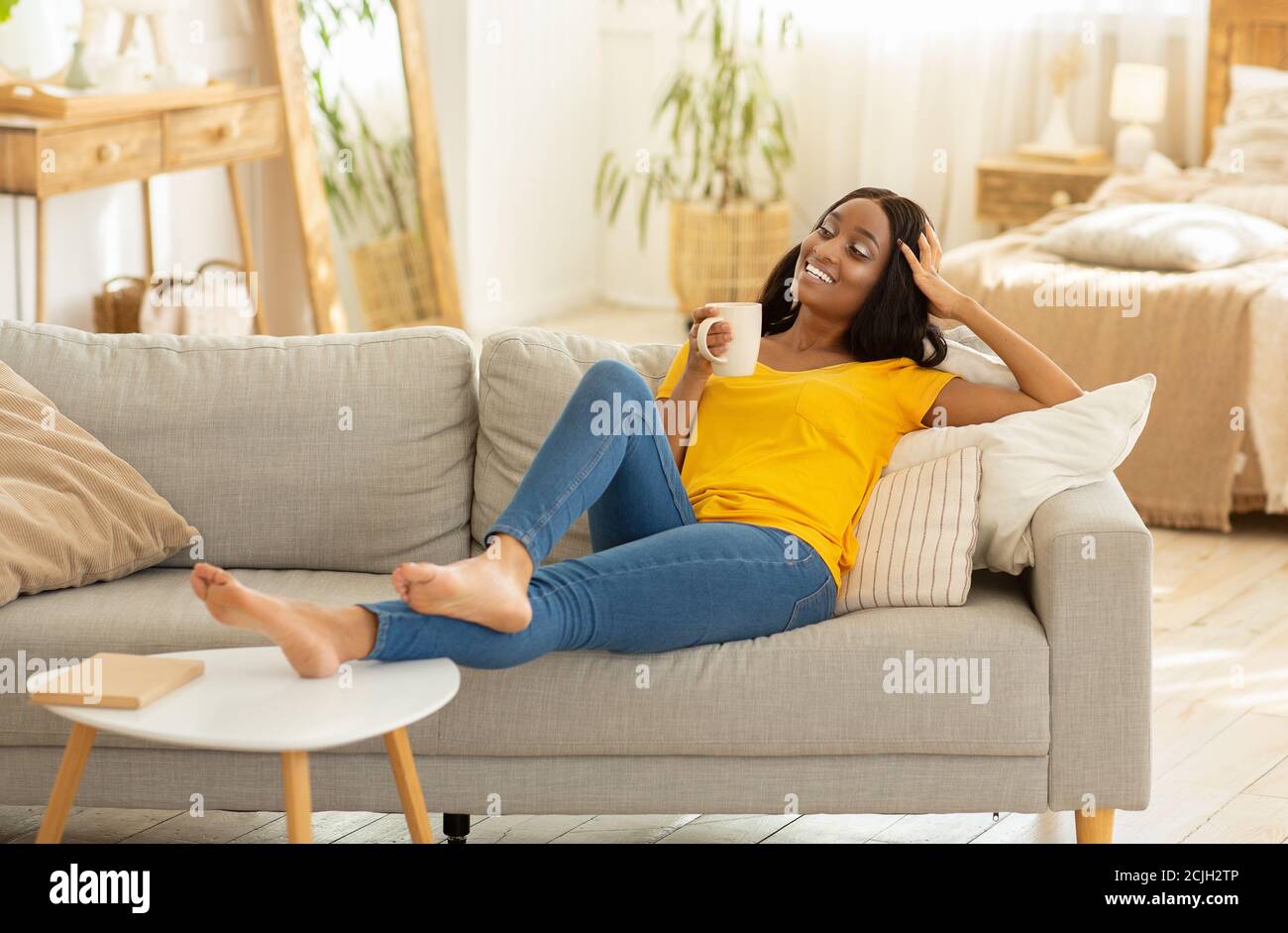 beautiful-young-black-woman-relaxing-on-sofa-with-cup-of-coffee-at-home