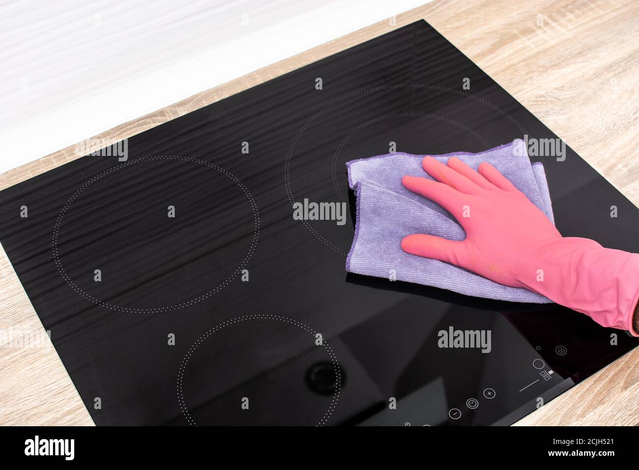 Cleaning a black electric induction cooktop Stock Photo
