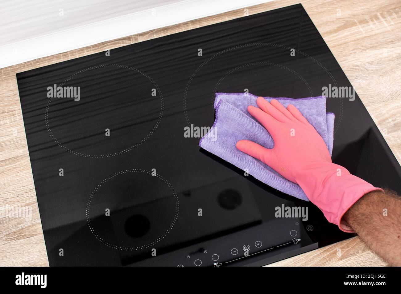 Cleaning a black electric induction cooktop Stock Photo