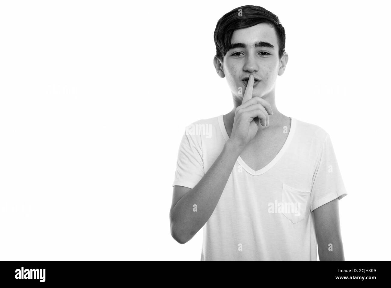 Studio shot of young handsome Persian teenage boy with finger on lips Stock Photo