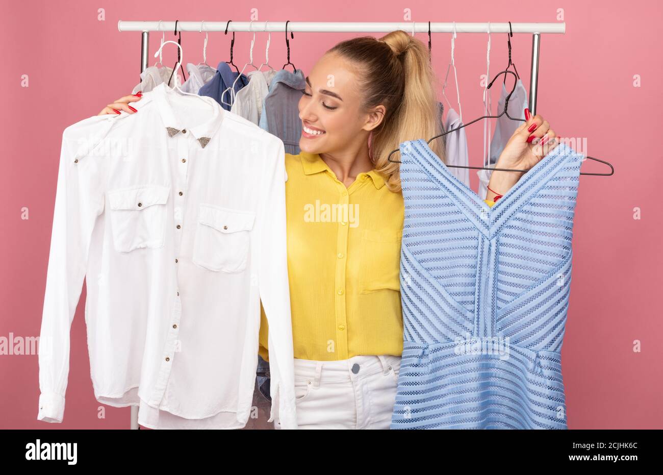 Young lady holding hangers with dress and shirt Stock Photo