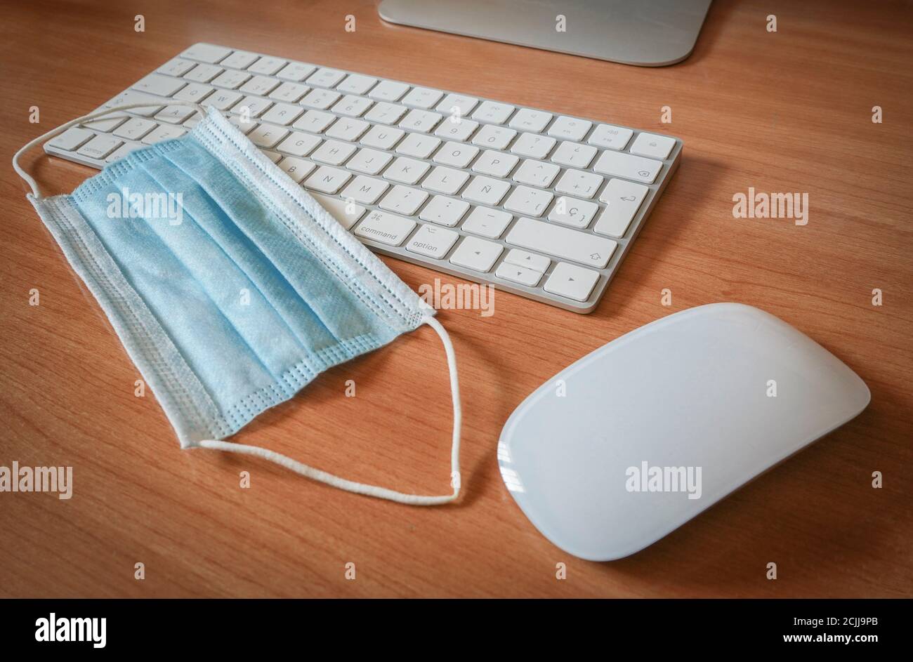 Surgical mask next to a keyboard and computer mouse. Concept of Covid pandemic and working. Stock Photo