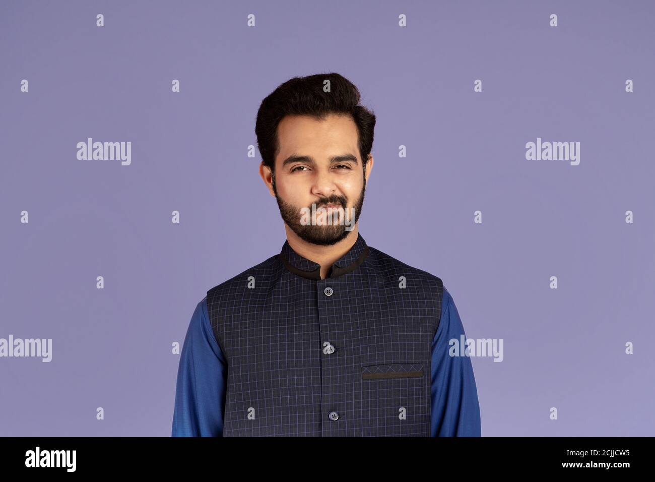 Handsome Indian guy expressing suspicion over violet background Stock Photo