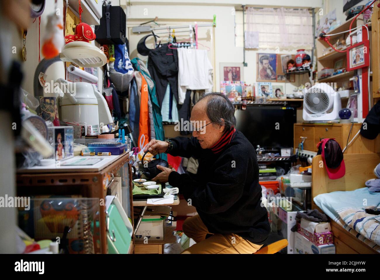Retired sailor Michael Sham, 73, pours tea in his one-room apartment in the Model Housing Estate in the North Point neighbourhood in Hong Kong, China, December 11, 2019. 'Many people at my age do not support the (protest) movement, but I do because I am a Hongkonger and I like human rights and democracy, which is something the Beijing government doesn't have,' Sham said, adding that he voted for the incoming pro-democracy district councillor James Pui. REUTERS/Thomas Peter      SEARCH 'NORTH POINT' FOR THIS STORY. SEARCH 'WIDER IMAGE' FOR ALL STORIES. Stock Photo