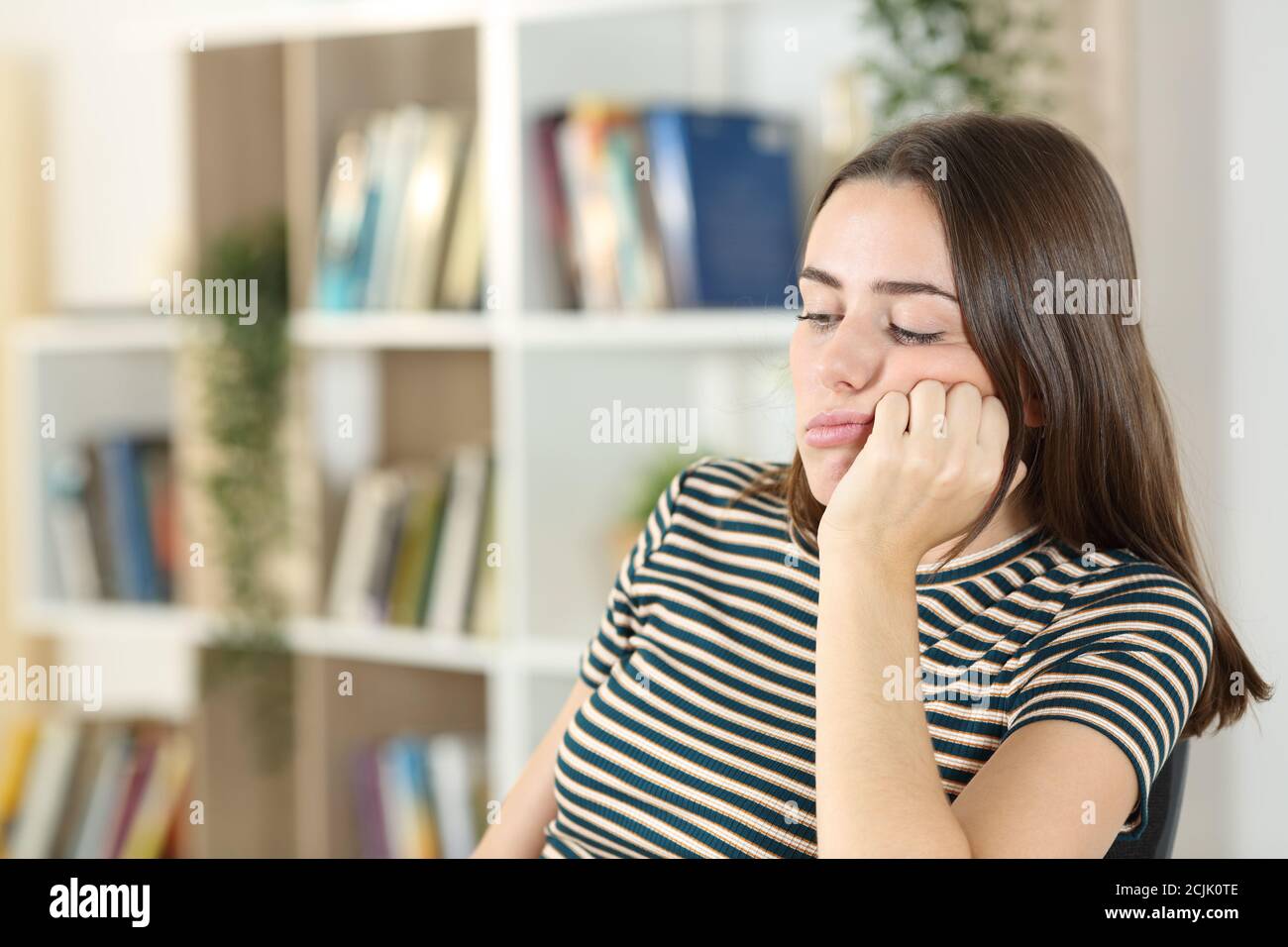 Bored teen wasting time sitting in the living room at home Stock Photo