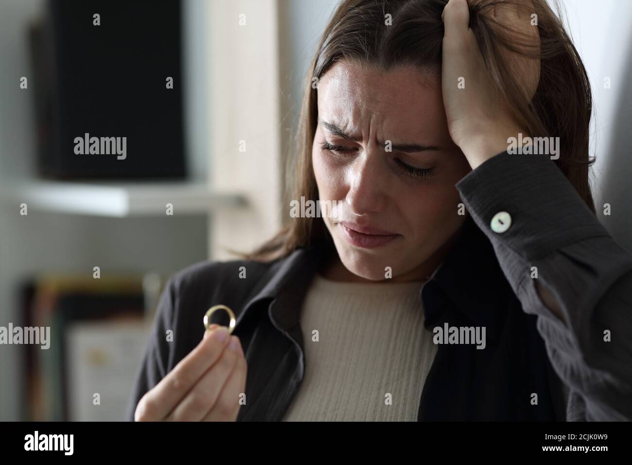 Sad wife complaining looking at wedding ring in the night at home Stock Photo