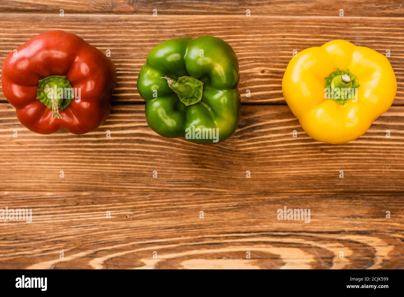 top view of colorful ripe bell peppers on wooden table Stock Photo - Alamy