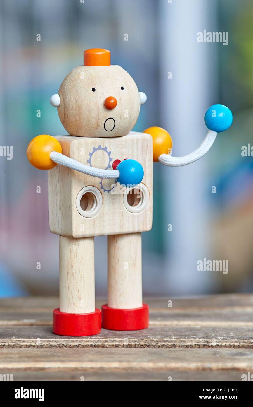 Wooden toy robot with red heart and surprise face. Defocused background. Stock Photo