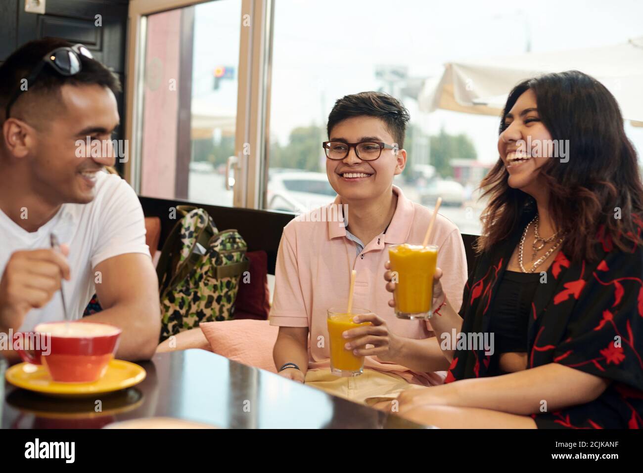 Meeting of friends. Three multi-ethnic friends are discussing something and laugh at it. Stock Photo