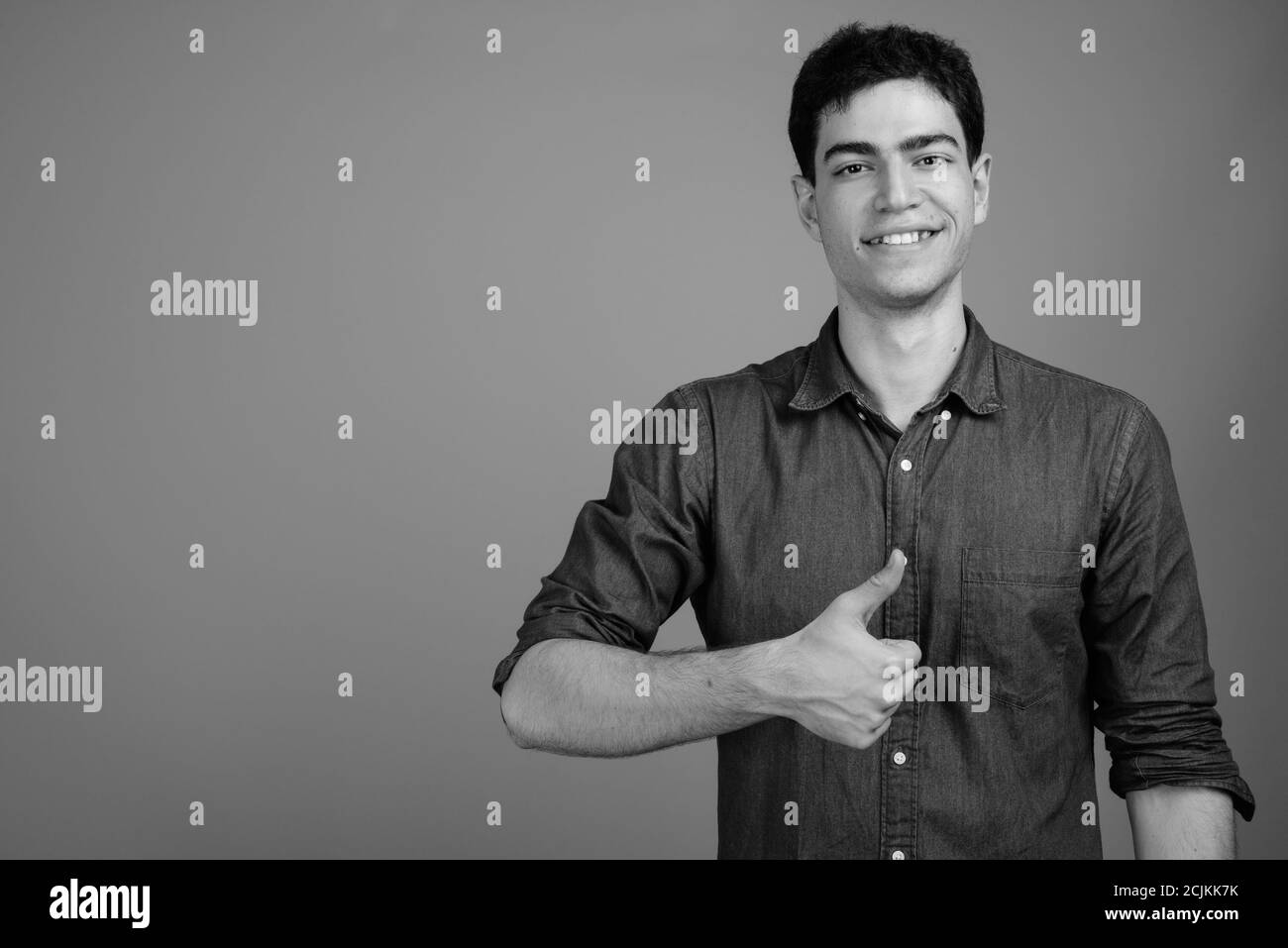 Portrait of happy young handsome Persian businessman giving thumbs up ...