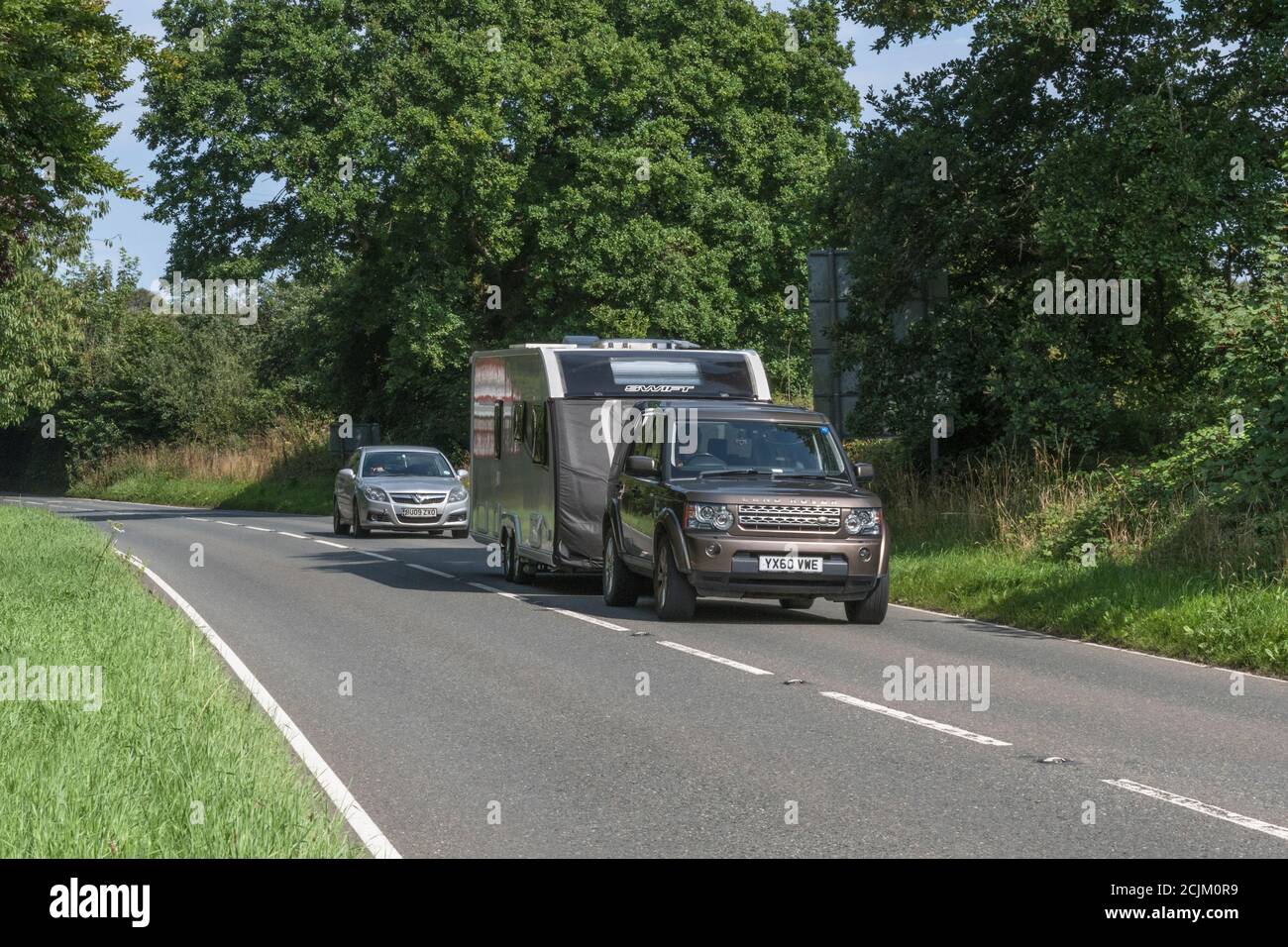 Car towing a caravan along a country road at Lostwithiel, Cornwall, during the summer holiday season. For staycations in UK, caravanning, UK holidays. Stock Photo