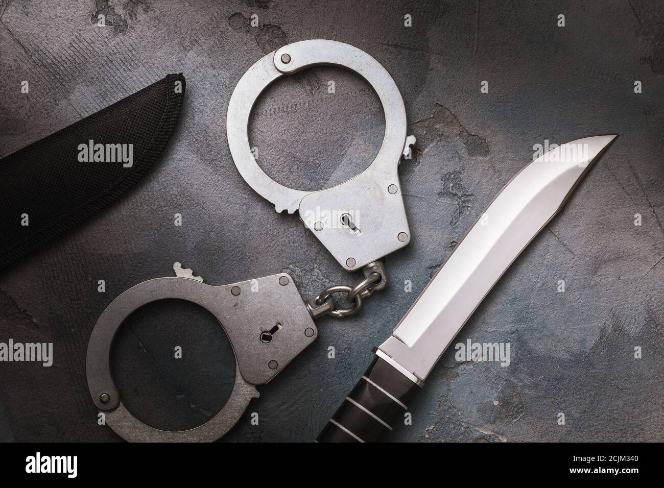 Handcuffs and a knife on the table, top view. Concept on the topic of