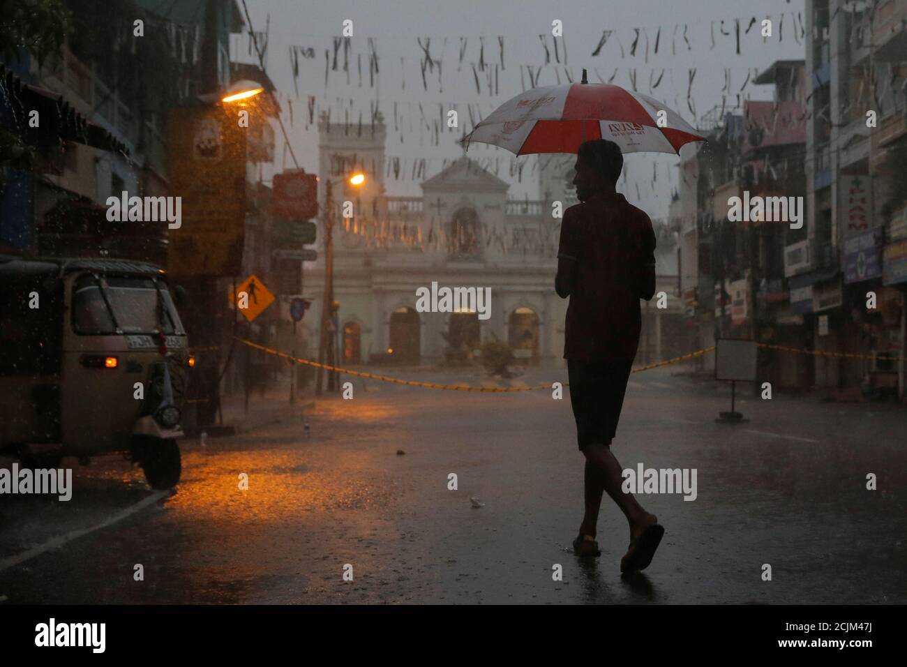 A man crosses a street during heavy rain near the security cordon surrounding St. Anthony's Shrine, days after a string of suicide bomb attacks on churches and luxury hotels across the island on Easter Sunday, in Colombo, Sri Lanka April 25, 2019. REUTERS/Thomas Peter Stock Photo
