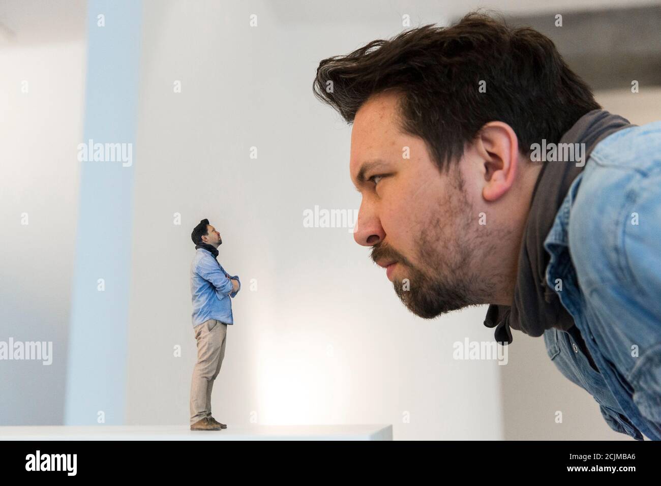 Twinkind co-founder Timo Schaedel looks at a 3D-printed figure of himself  at the Twinkind 3D printing studio in Berlin, December 13, 2013. A  3D-printed likeness is produced by taking a 360 degree