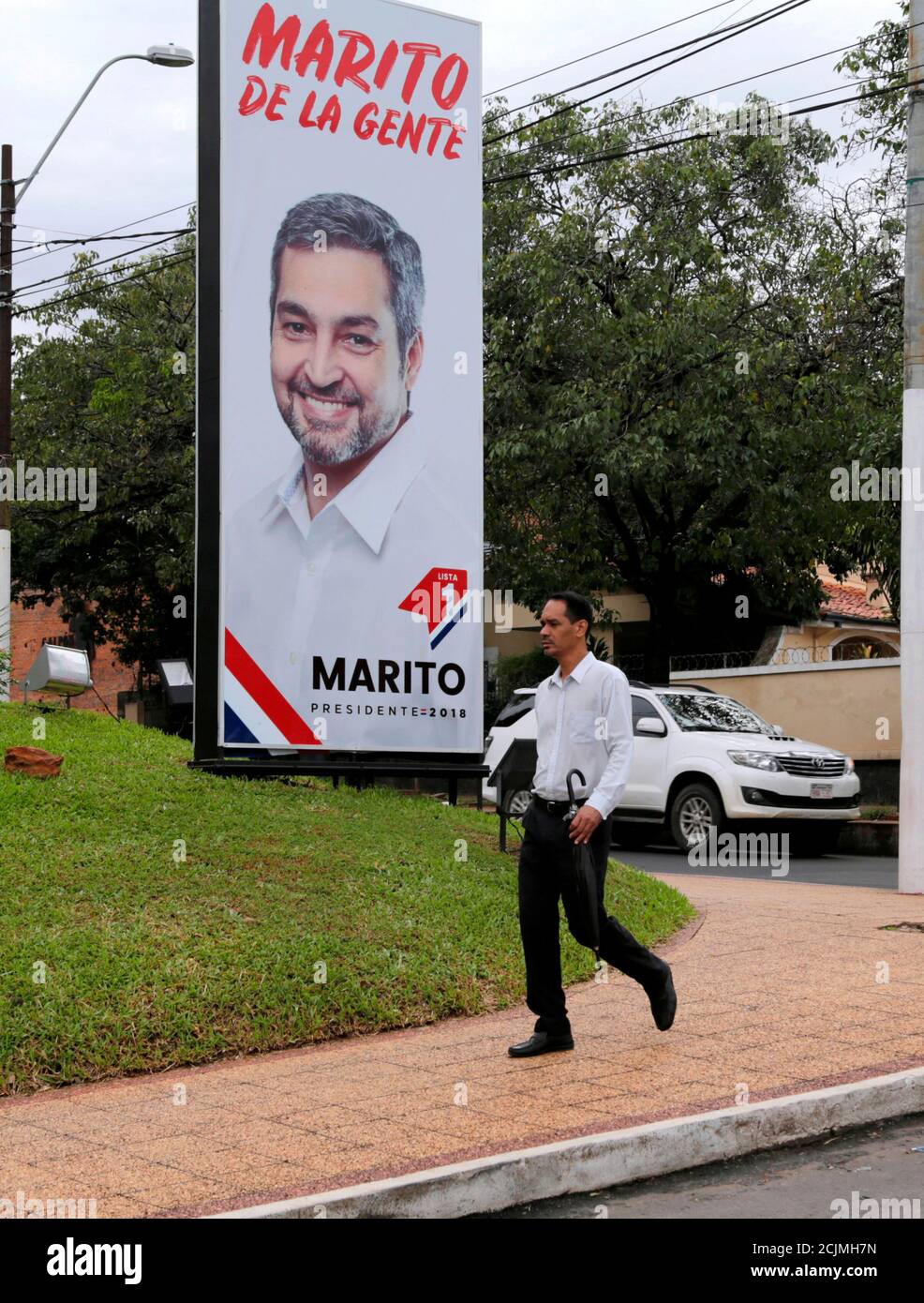 A man walks in front of a banner, displaying Paraguay's presidential candidate Mario Abdo Benitez, of the Colorado Party in Asuncion, Paraguay March 21, 2018. REUTERS/Jorge Adorno Stock Photo