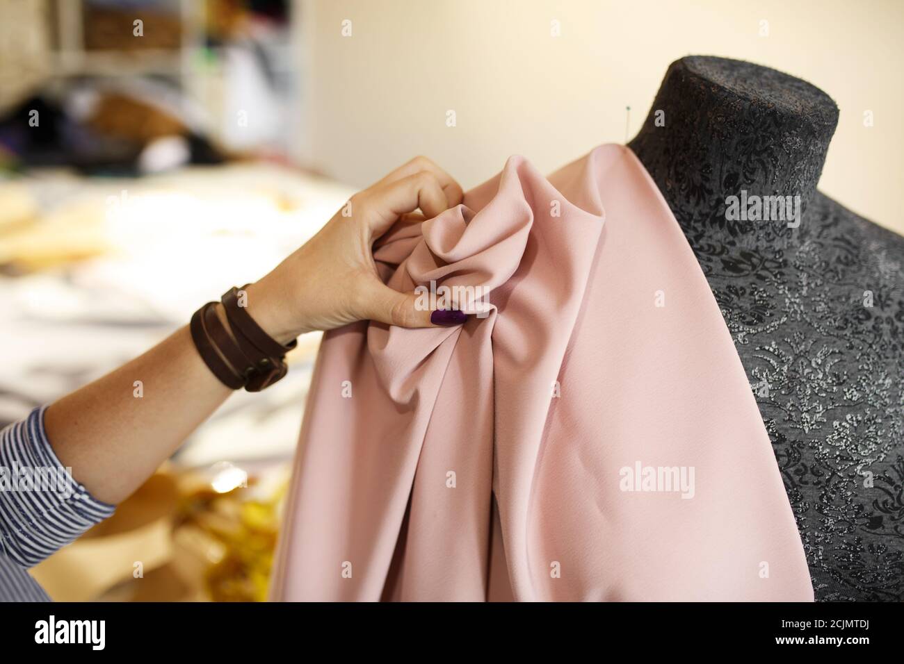 female dressmaker attach fabric to mannequin with needles. creating