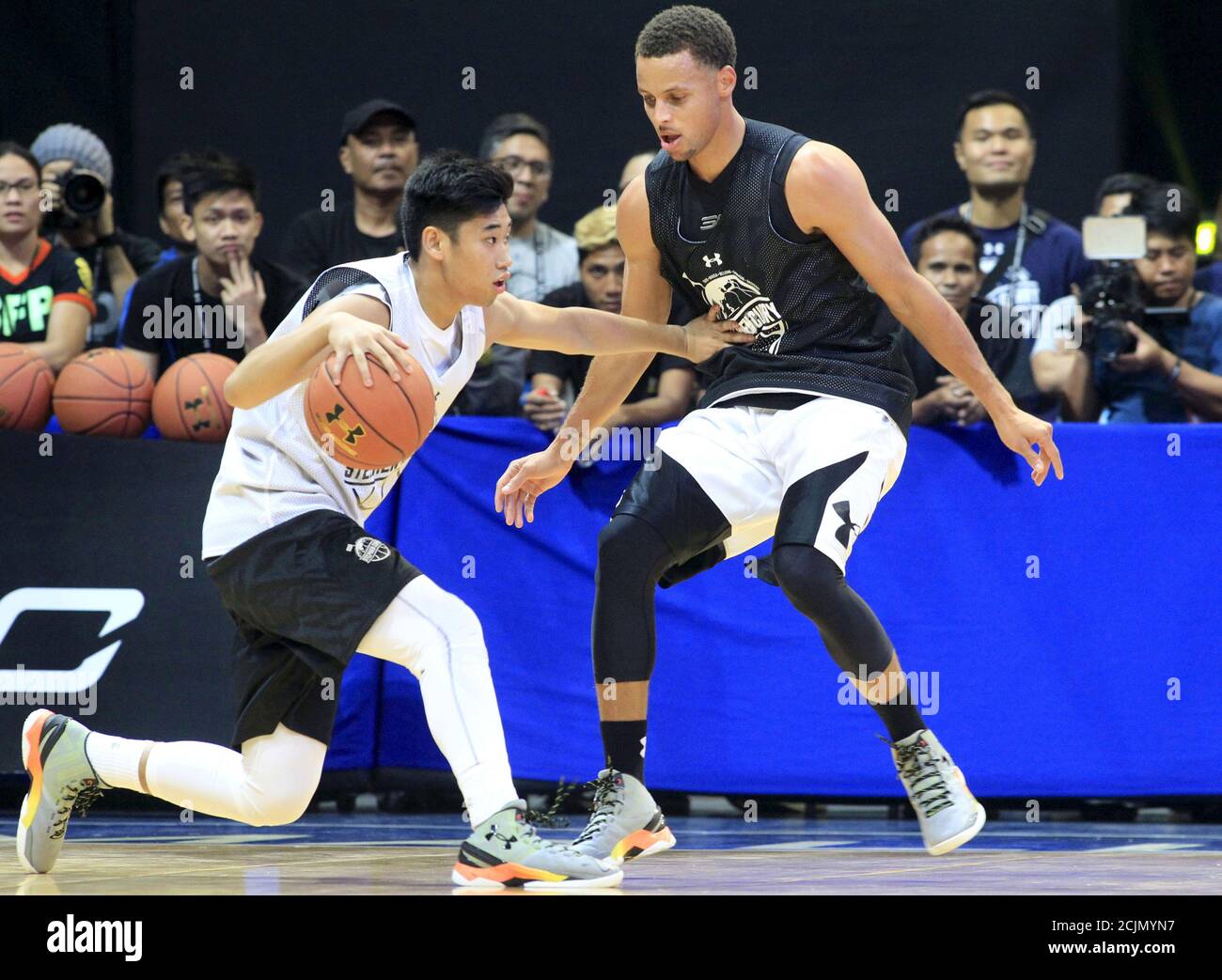 NBA Golden State Warriors Most Valuable Player (MVP) Stephen Curry (R)  guards a local player during an exhibition basketball game in Manila  September 5, 2015. Curry arrived in Manila on Saturday for