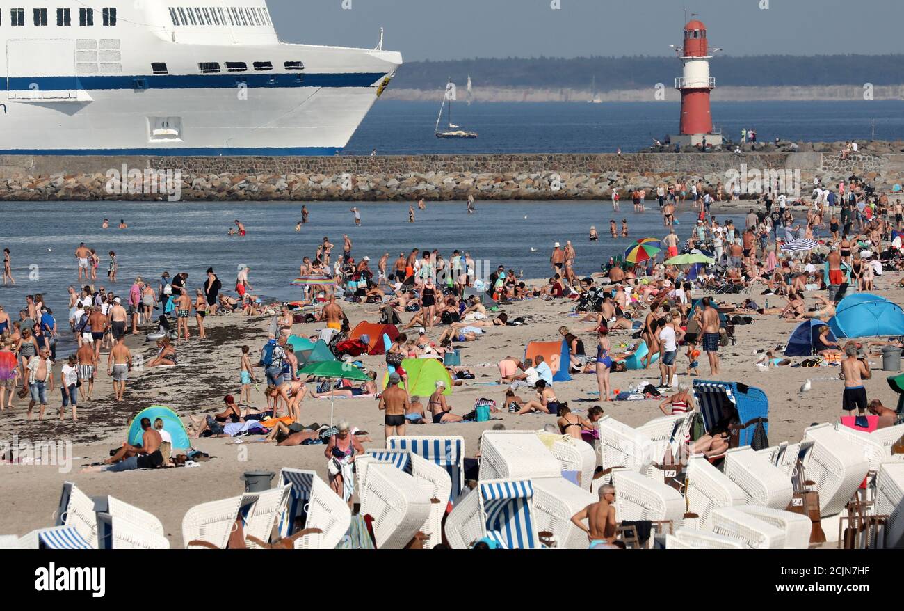 15 September 2020, Mecklenburg-Western Pomerania, Warnemünde: Swimmers enjoy the unusually warm late summer weather on the Baltic Sea beach, with the Swedish ferry 'Nils Holgersson' from TT-Line arriving on the left. The heat of September brings temperatures of up to 34 degrees in Germany, even in the 'cool' north temperatures reach the 30 degree mark. Photo: Bernd Wüstneck/dpa-Zentralbild/dpa Stock Photo